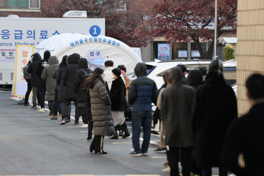 코로나19 신규 확진자가 1200명대를 기록한 25일 오전 서울 중구 국립중앙의료원에 마련된 해외출국선별진료소에 시민 및 외국인들이 검사를 받기 위해 줄을 서 있다.  연합뉴스